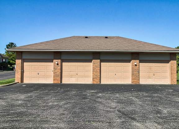 A two-car garage with a brick pillar and tan doors.