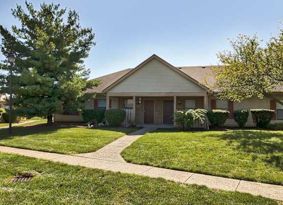 A house with a well-maintained lawn and a sidewalk in front.
