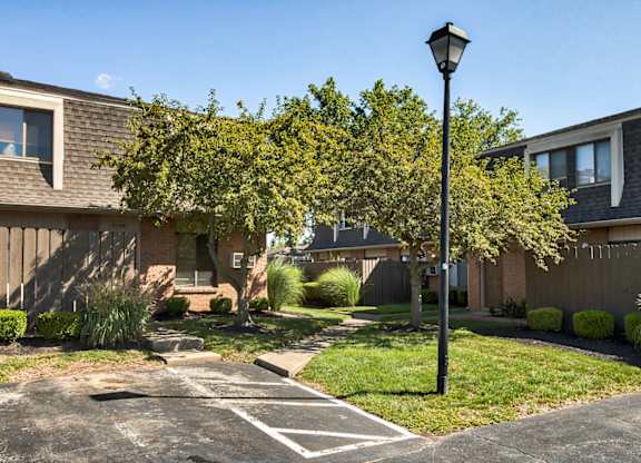 A black lamp post stands in a driveway with a house in the background.