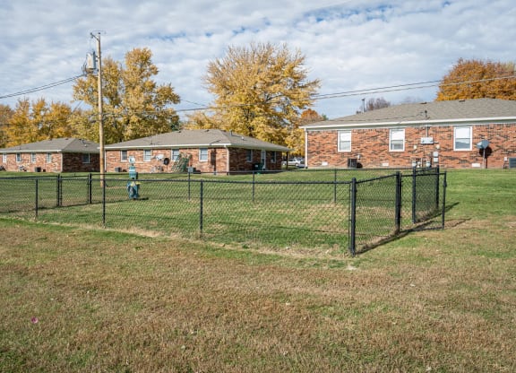 a fenced in dog park in front of a brick building at Stonebrook of Franklin, Franklin, IN, 46131