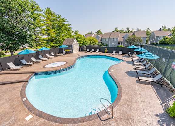 A large outdoor swimming pool surrounded by lounge chairs and umbrellas.
