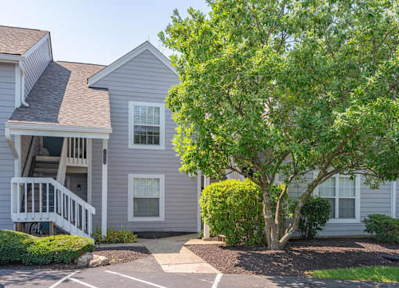 A grey house with a tree in front.