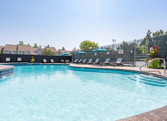 A large swimming pool with a metal fence and sun loungers.