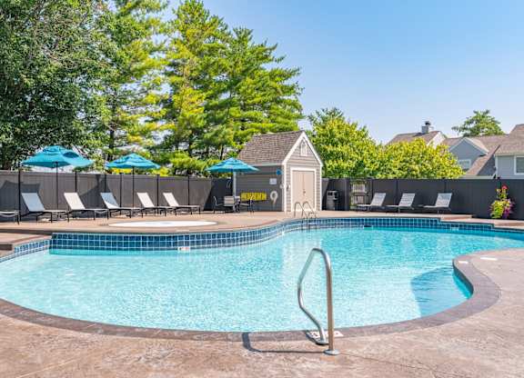A swimming pool surrounded by lounge chairs and umbrellas.