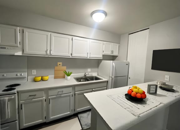 a kitchen with white cabinets and a counter with a bowl of fruit