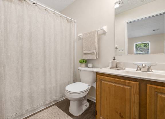 A white toilet sits in a bathroom with a beige shower curtain.