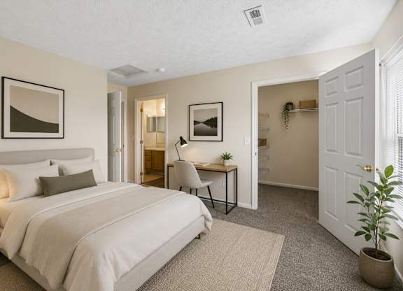 A bedroom with a large bed and a desk with a chair.