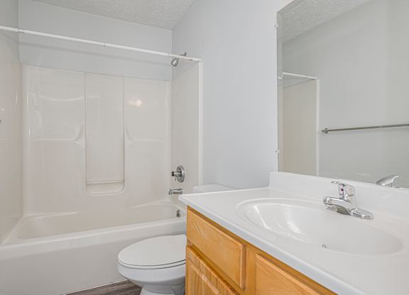 A white bathroom with a toilet, sink, and bathtub.