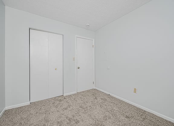 A room with two doors and a carpeted floor.