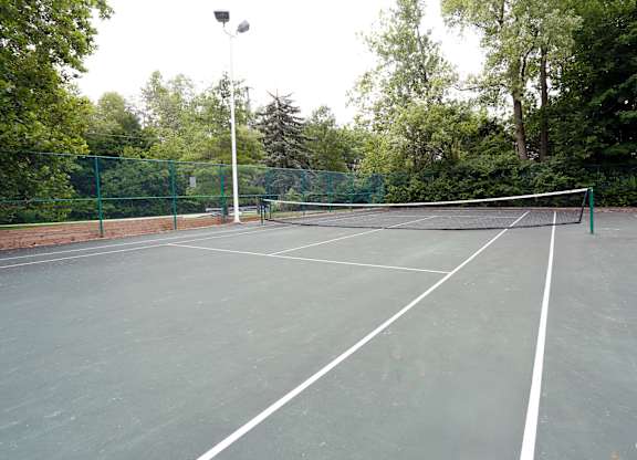 A tennis court surrounded by a green fence.