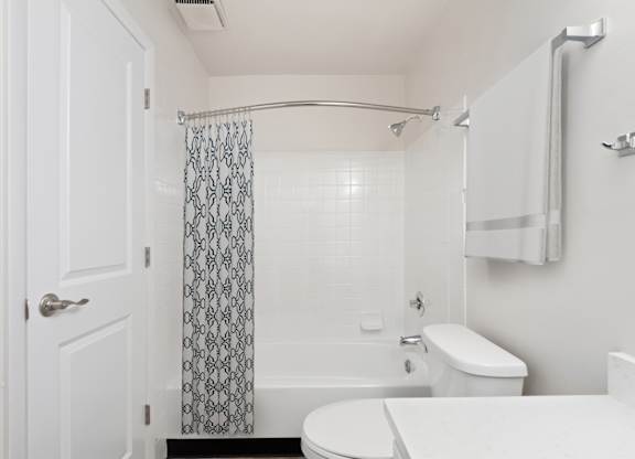 A white bathroom with a toilet, sink, and shower.