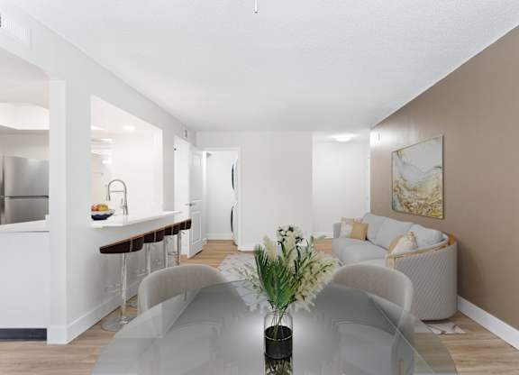 A modern living room with a glass table and grey chairs.