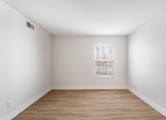 A room with a window and wooden flooring.