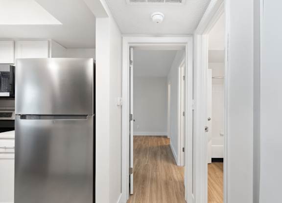 A long hallway with a refrigerator on the left.
