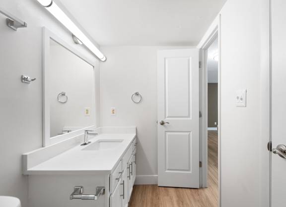 A white bathroom with a sink, mirror, and toilet.