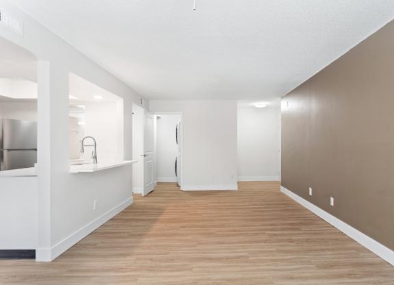 A long, empty hallway with white walls and wood flooring.