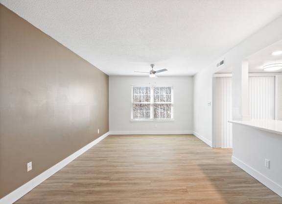A spacious room with wooden floors and a ceiling fan.