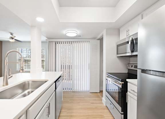 A modern kitchen with stainless steel appliances and white countertops.