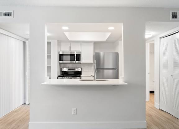 A modern kitchen with white cabinets and appliances.
