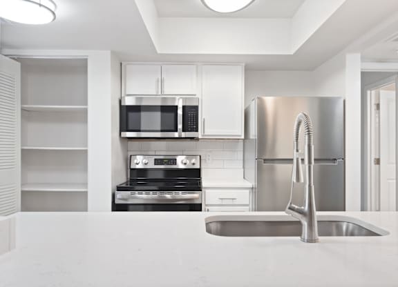 A modern kitchen with stainless steel appliances and white cabinetry.