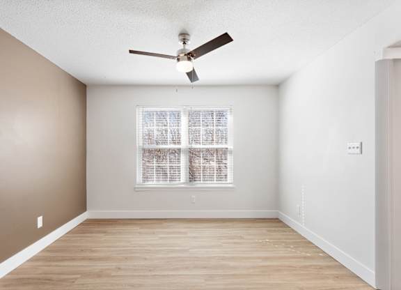 A room with a ceiling fan and a window with blinds.