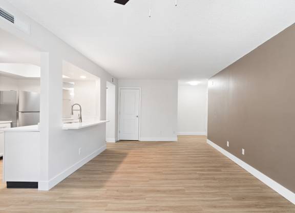 A room with a white kitchen area and a wooden floor.