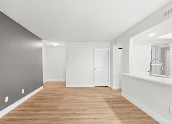 A long, empty room with wooden floors and white walls.