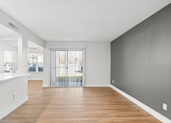 A spacious room with wooden floors and white walls.