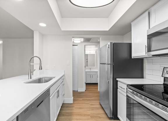 A modern kitchen with white cabinets and stainless steel appliances.