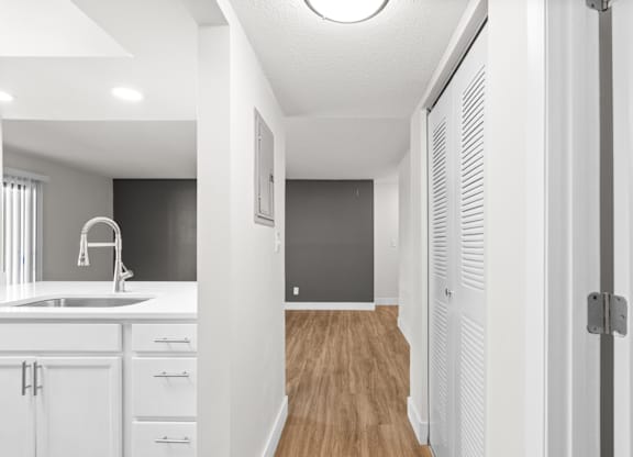 A modern kitchen with white cabinets and a wooden floor.