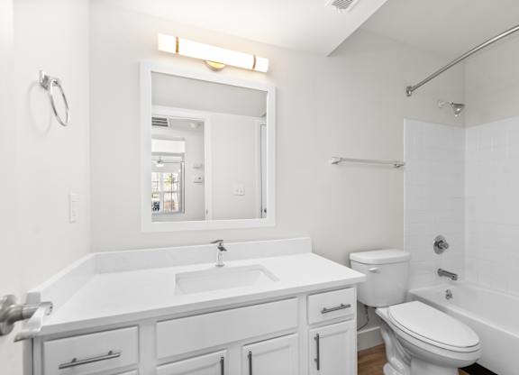 A white bathroom with a sink, toilet, and bathtub.