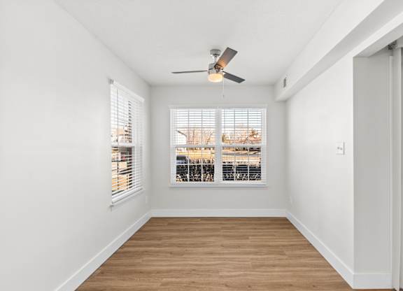 A room with a ceiling fan and a window overlooking a cityscape.