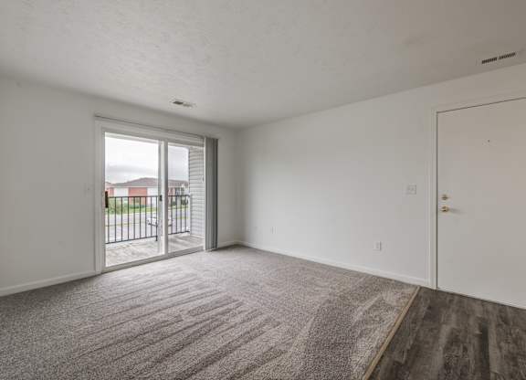 an empty living room with a door to a balcony
