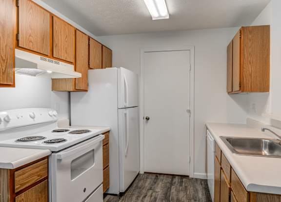 an empty kitchen with white appliances and wooden cabinets
