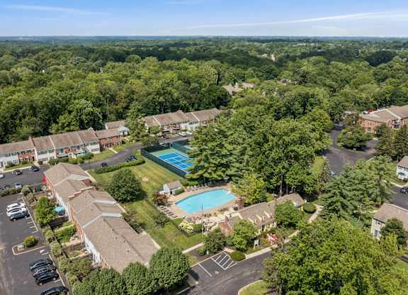 An aerial view of a residential complex with a swimming pool surrounded by trees.