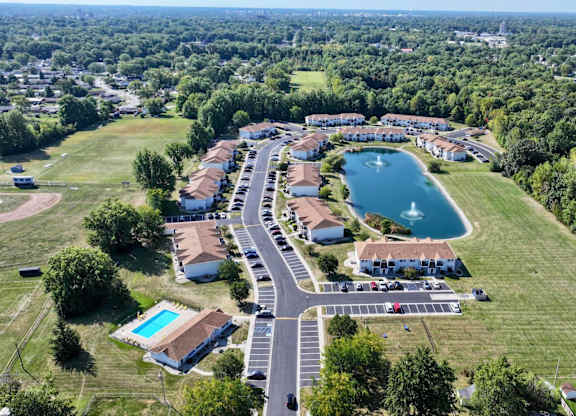 A bird's eye view of a residential area with a lake and a swimming pool.