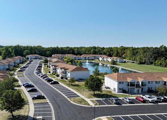 A sunny day at a residential complex with a pond and greenery.