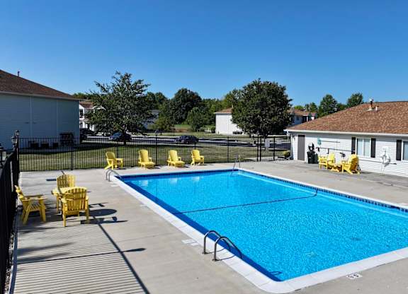 A large outdoor swimming pool surrounded by yellow chairs.