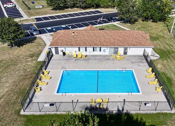 An aerial view of a pool with yellow lifeguard chairs and a building with a red roof.