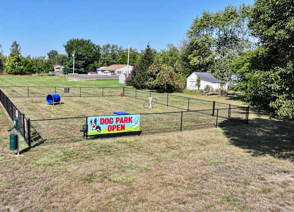 A sign that says Dog Park Open is on a fence.