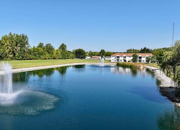 A fountain in the middle of a lake surrounded by trees.