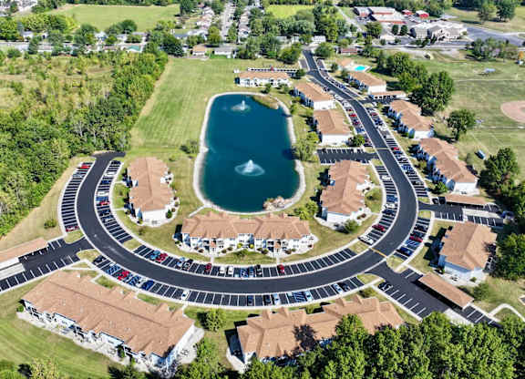 A bird's eye view of a roundabout with a lake in the middle of a residential area.