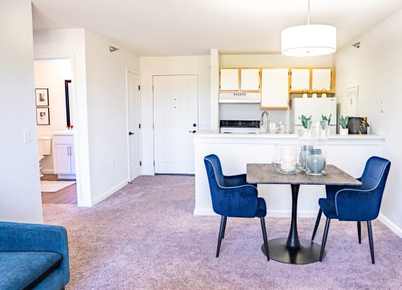 a dining area with a table and chairs and a kitchen in the background