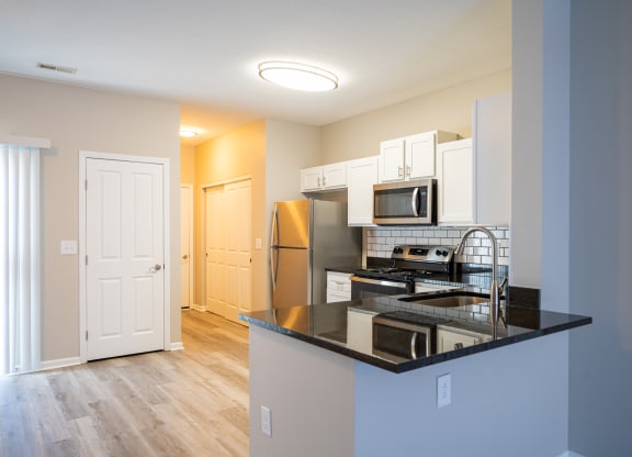 a kitchen with a black counter top and a stainless steel refrigerator at Traditions at Slate Ridge, Reynoldsburg, OH 43068