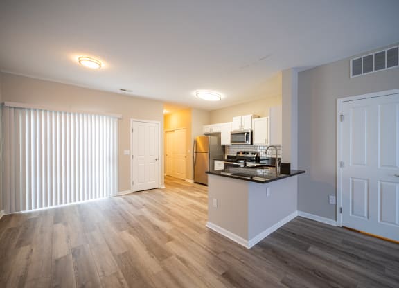 a living room with a kitchen and a door to a hallway at Traditions at Slate Ridge, Reynoldsburg, 43068