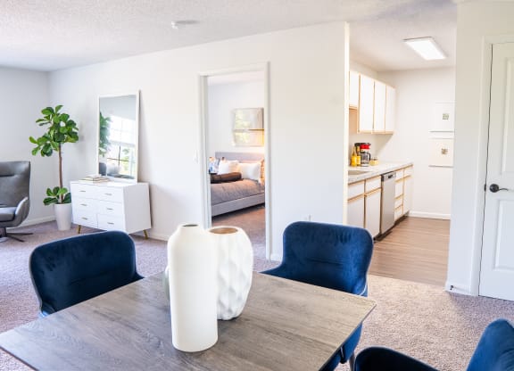 a living room with a dining room table and chairs and a kitchen in the background