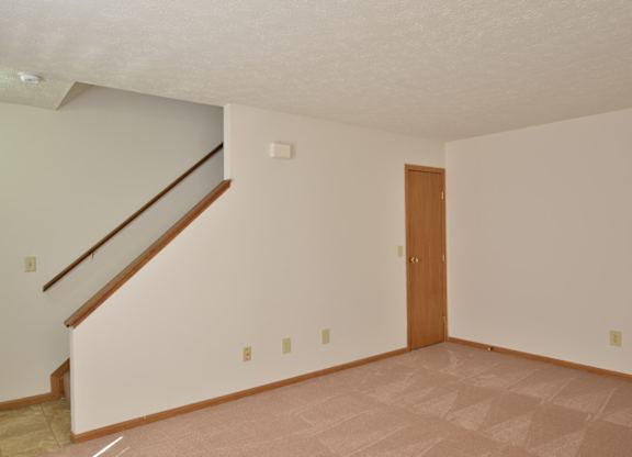 A room with a wooden door and a staircase.