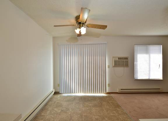 A room with a ceiling fan and a window with blinds.