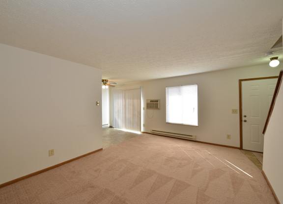 A large empty room with a carpeted floor and white walls.
