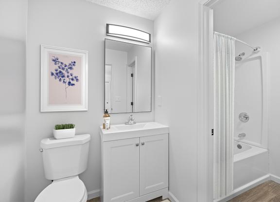 A white bathroom with a toilet, sink, and shower.